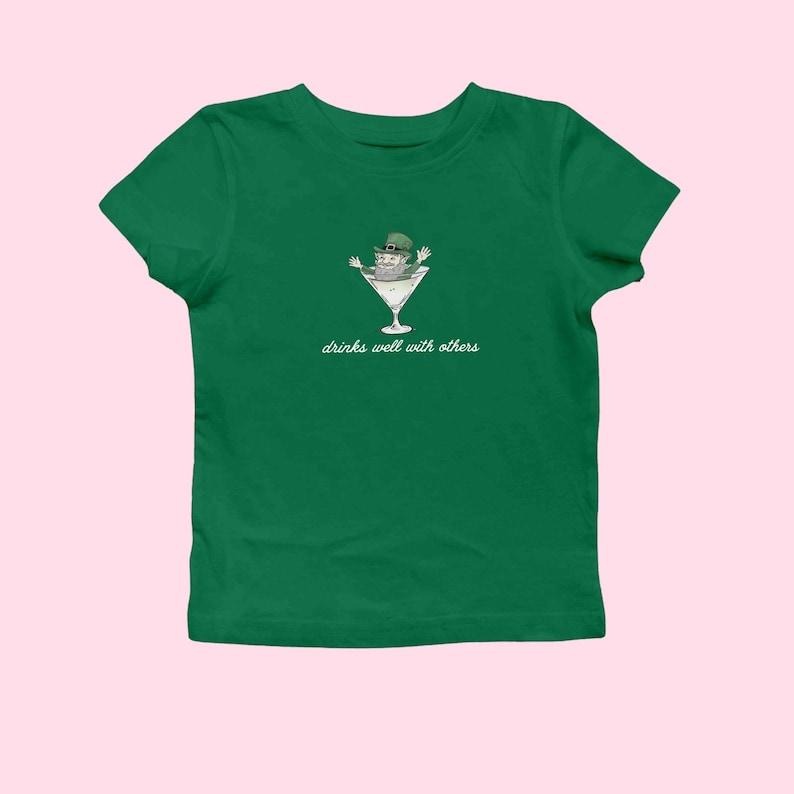 St Patrick's Day Baby Tee for Women, Leprechaun Martini Cocktail Drinks Well With Others Baby Tee St Patty Day Shirt Funny St Paddy Tee